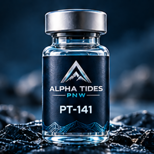 PT-141 vial with silver cap and navy Alpha Tides PNW label on a rocky coast